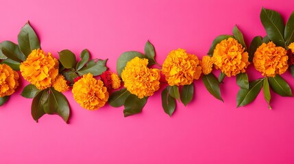 Obraz premium Arrangement of orange marigold flowers with green leaves on a vibrant pink background top view flat lay