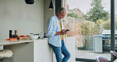 Senior man in kitchen, relax with phone and morning breakfast, calm morning and checking social media. Home, online recipe and elderly person with smartphone, smile and reading email on mobile app.