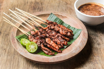 Chicken satay dish on a plate with banana leaves and peanut sauce.traditional Indonesian food.