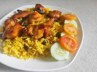 Nasi Biryani or Biryani Rice with honey roasted chicken on a white plate