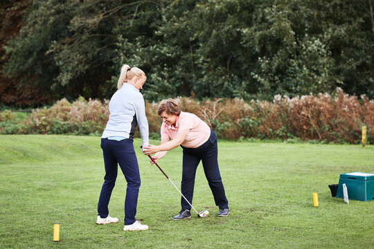 Golf course, coach and teaching woman at club, field or outdoor in nature to help at lesson. Golfers, instructor or person learning to hold driver, exercise or training together for sports in summer
