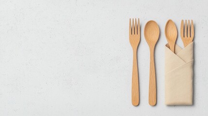 A minimalist arrangement of wooden cutlery, including forks and spoons, neatly placed beside a folded napkin on a textured surface.