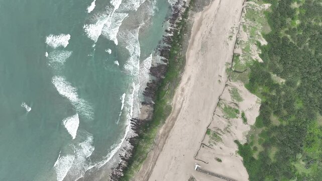 Aerial view of a sandbar and coastal shoreline along Taiwan&rsquo;s northeast coast, with waves surrounding the sand formation.