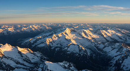 Fototapeta premium Snow Capped Mountain Range Aerial View at Sunrise with Golden Light