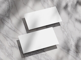 Clean, white business card mockup on a polished marble backdrop with natural light shadows.