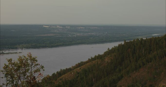Contemplating vast river landscape and distant city from mountain peak