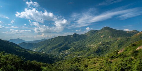 Obraz premium Breathtaking Scenic View of Lush Green Mountains Under Clear Blue Sky with Soft Clouds in Tranquil Natural Environment