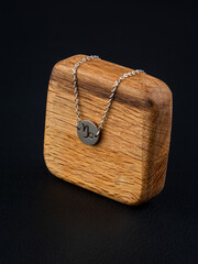 close up silver bracelet horoscope with Capricorn  sign  on a wooden base on a black background