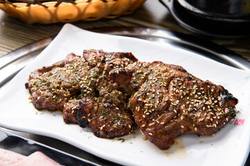 There is seasoned meat on a white plate.
