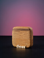 close up gold pendant horoscope with Gemini   sign on a wooden base  on a pink background