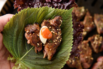 Seasoned meat and sauce-covered garlic are placed on top of the ssam vegetables.
