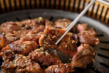 A picture of a person holding a bite-sized piece of meat with chopsticks
