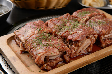 Six pieces of seasoned ribs are rolled up on a wooden plate.
