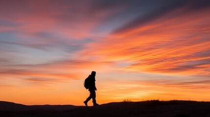 Silhouette of Person Hiking at Sunset with Dramatic Orange and Red Sky