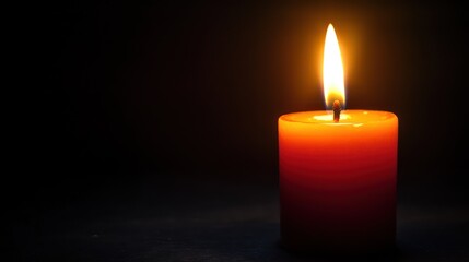 Single red candle burning in dark background