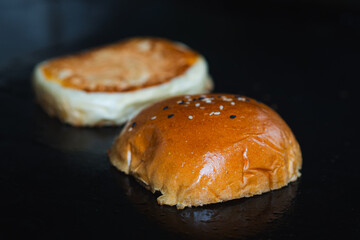 Toasted hamburger bun halves cooking on griddle, food preparation before assembling burgers.