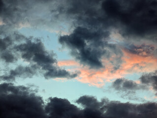 Fototapeta premium Dramatic and colorful sky with dark clouds and soft pink light during sunset, evening twilight and dusk cloudscape, vivid and moody atmosphere, blue and grey cloudy nature landscape.