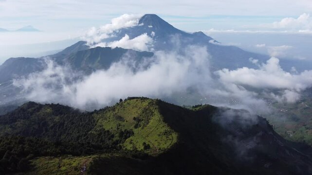 Aerial view of Mount Prau, Central Java, Indonesia, captured on April 28, 2025. Rolling green hills and misty peaks create a stunning natural landscape under the clear blue sky