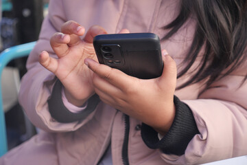  child using smartphone while sitting at an outdoor table