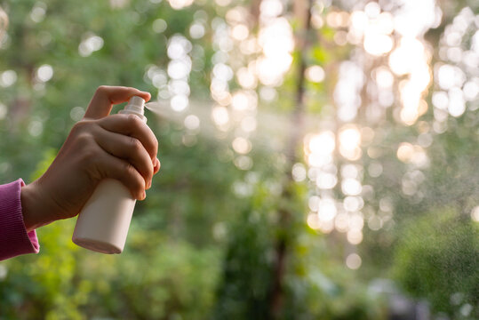 Hand applying insect repellent mosquito insecticide spray to kill flies bugs and mosquitoes on skin outside. Malaria zika virus and dengue fever prevention. Protective measures