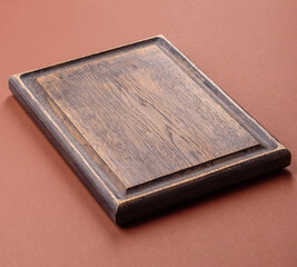 Empty wooden cutting board on a monochrome brown background