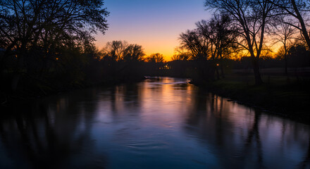 Picturesque River Flows Into The Distance At Sunset Near Shadowy Trees