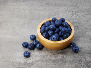 Blueberries in wooden bowl on stone texture background