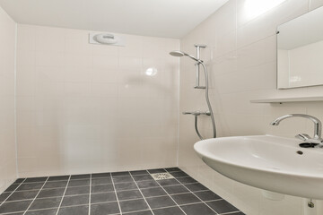 A sleek and contemporary bathroom design featuring a shower, sink, and minimalist tiles. The light color palette adds a clean aesthetic to the space.