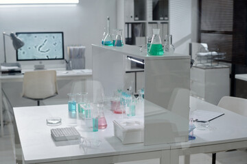 Laboratory scene showing several beakers and flasks containing colorful liquids and chemical substances on laboratory tables