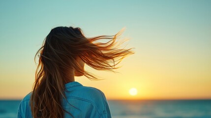 Obraz premium Back View of a Person with Long Hair and Wind Blowing at Sunset by the Ocean Shore