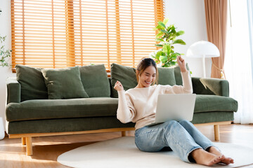 Funny euphoric young asian woman celebrating winning or getting ecommerce shopping offer on computer laptop. Excited happy girl winner looking at notebook celebrating successq