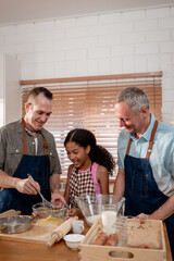 Caucasian senior gay couple baking bakery with adopted daughter in house. 