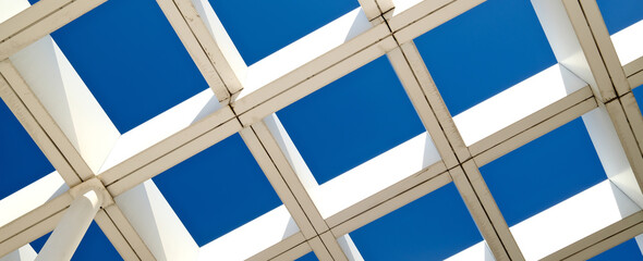 Striking modern architecture with geometric white pergola structure against deep blue sky....