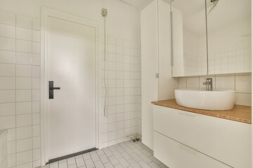 Bright and airy bathroom featuring white tiled walls, a sleek vanity with bowl sink, and ample storage space, ideal for contemporary living.