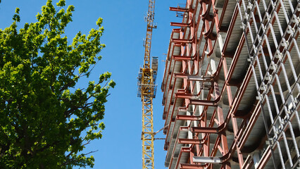 Construction site showing modern building framework with exposed steel beams, metal support structures and industrial scaffolding