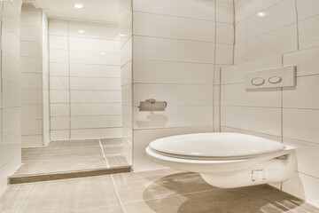 A contemporary bathroom featuring sleek white tiles, a modern toilet, and a minimalist aesthetic. The spacious design emphasizes cleanliness and elegance.