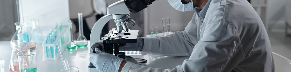 Researcher conducting scientific experiment in a well-equipped laboratory, wearing lab coat and gloves, working with various laboratory equipment