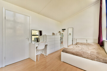 A bright, modern bedroom featuring a simple bed, desk, and storage. The clean lines and neutral colors create a serene and inviting atmosphere.