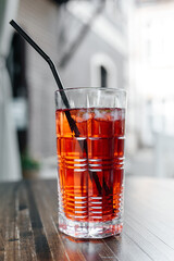 strawberry coctail on wooden table in street cafe, red coctail with mint, ice and straw