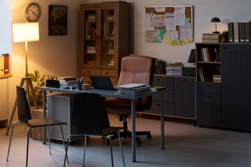 Part of spacious modern office of counselor with lamp, armchair, desk with laptop and paper documents and two chairs