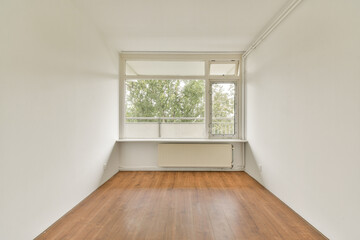 A spacious, minimalist interior room featuring wooden flooring and large windows allowing natural...