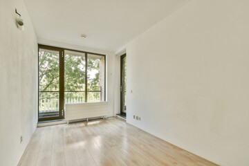 Bright and airy interior space featuring large windows that allow natural light to flood in. The floor is made of light-colored wood, enhancing the minimalist design.