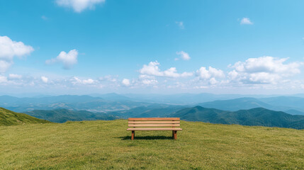 Serene bench sits on grassy hill, overlooking vast mountain range under bright blue sky
