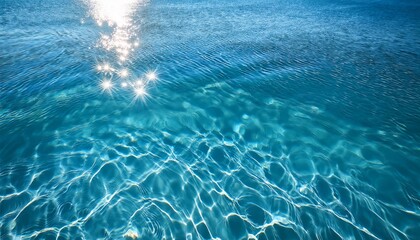 Fototapeta premium Sunlight sparkles on the surface of clear blue water, creating a serene and refreshing scene.