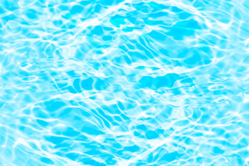 Blue water with ripples on the surface. Defocus blurred transparent blue colored clear calm water surface texture with splashes and bubbles. Water waves with shining pattern texture background.
