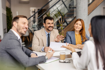 Group of businesspeople sitting at corporate office and discussing project and paperwork.