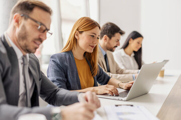 Leadership team with laptop and paperwork collaborating on a project at boardroom in corporate firm.