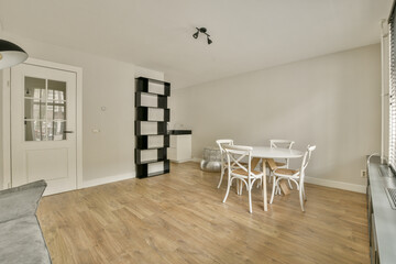 A spacious, well-lit room featuring minimalist furniture, a sleek dining table, and a light-colored...