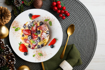 French clafoutis tart with red berries. Top view with christmas decorations.