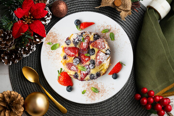 French clafoutis tart with red berries. Top view with christmas decorations.